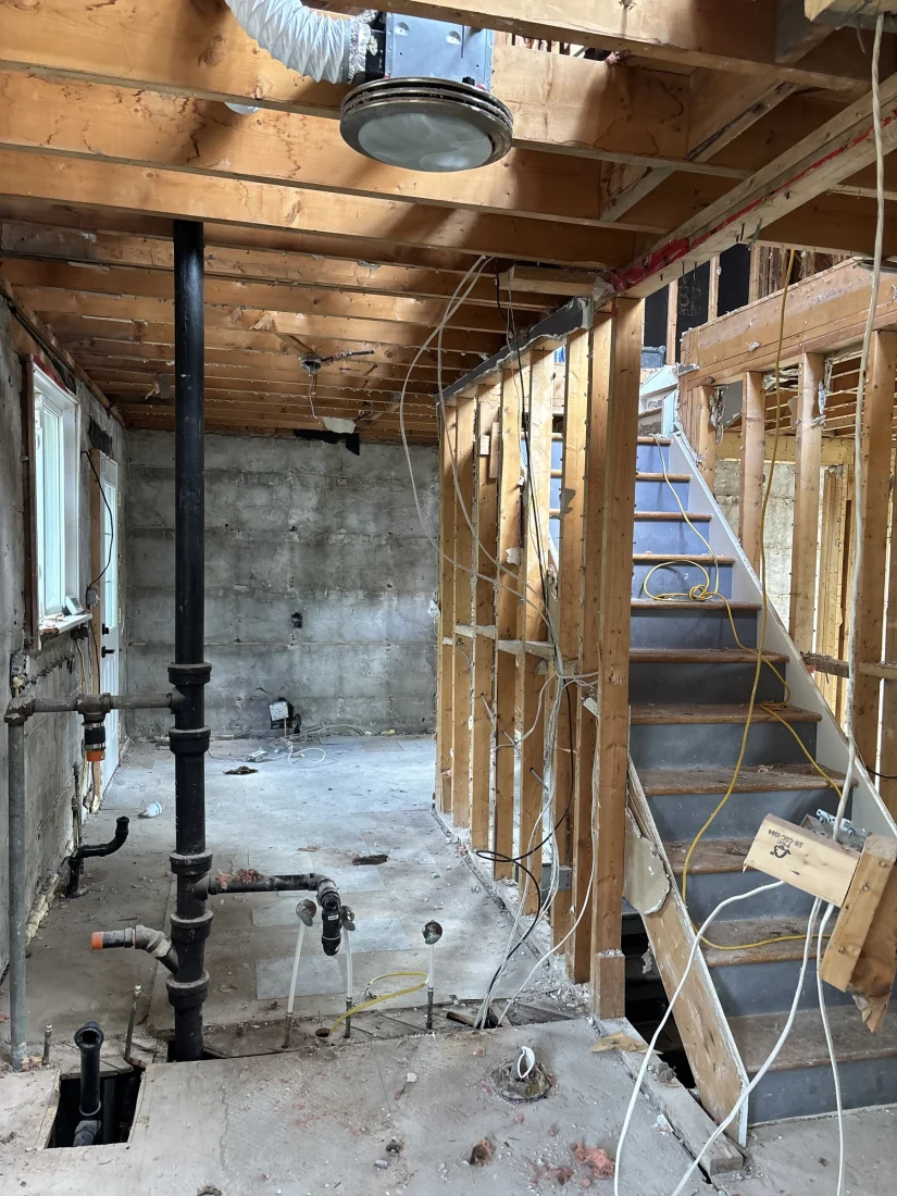 Basement gutted with the plumbing stack and stairs exposed