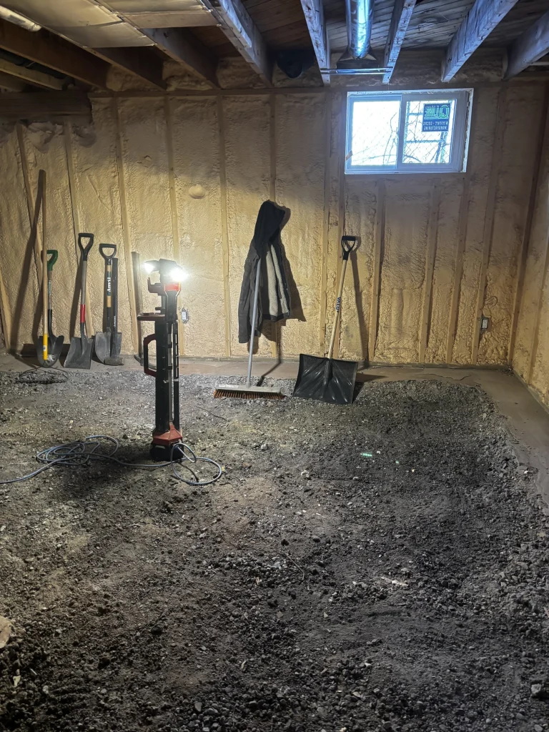 Basement floor slab broken out by hand, with shovels and a work light