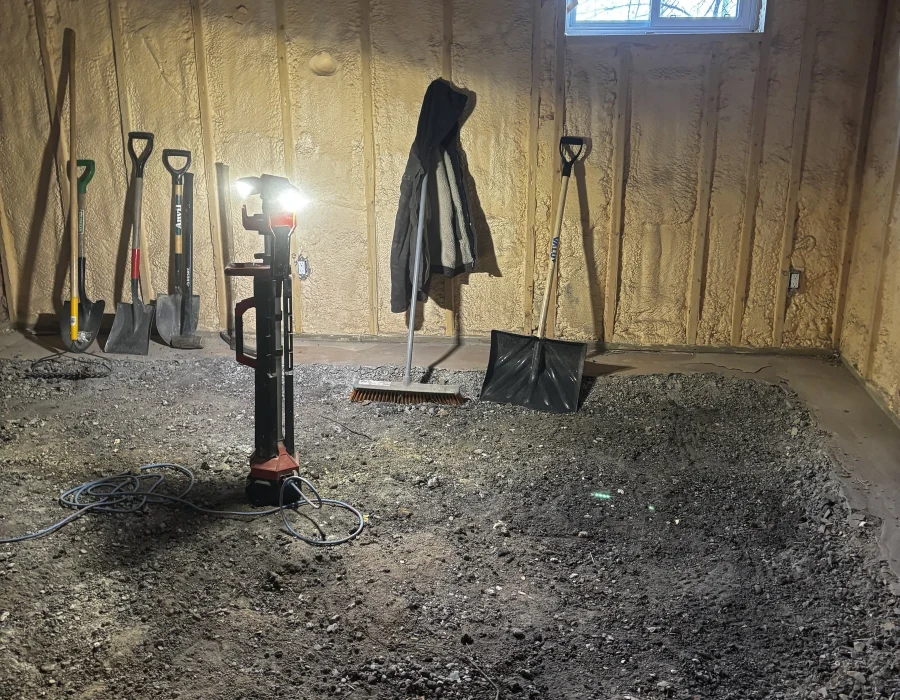 Basement floor slab broken out by hand, with shovels and a work light