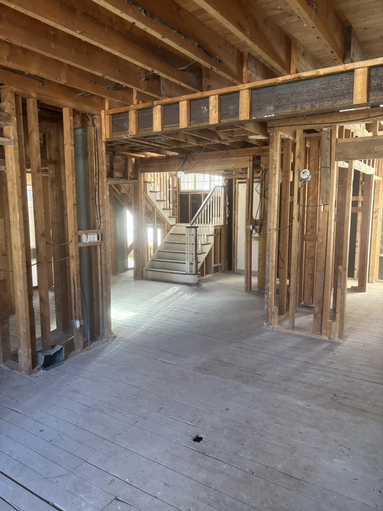 Gutted main floor with the staircase and studs exposed