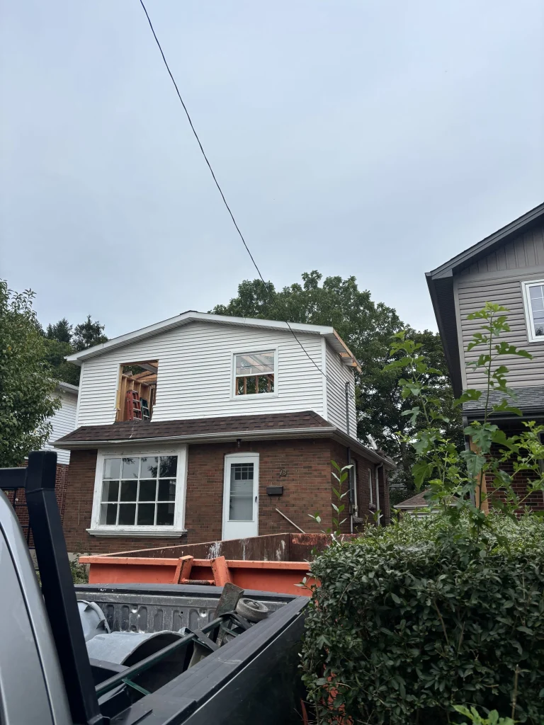 Roll-off bin in the driveway of a two-storey brick house
