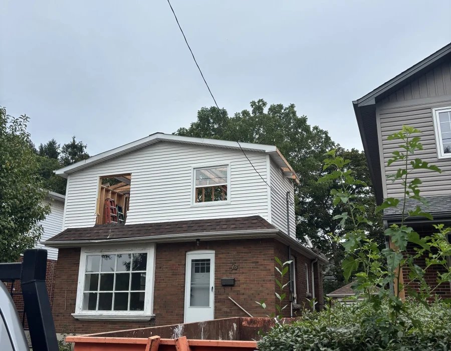 Roll-off bin in the driveway of a two-storey brick house